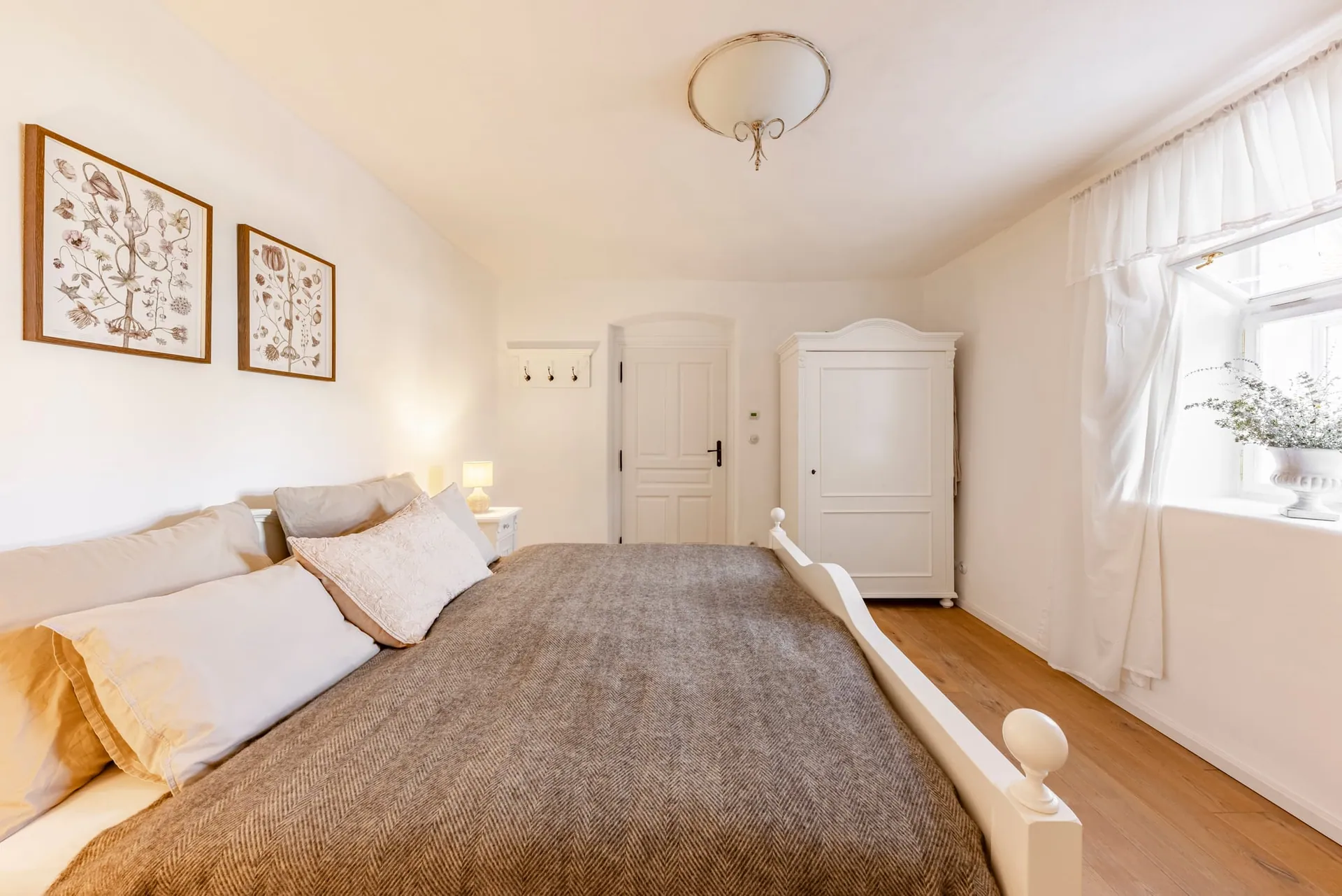 View across the double bed towards the door, white wardrobe and curtained window.