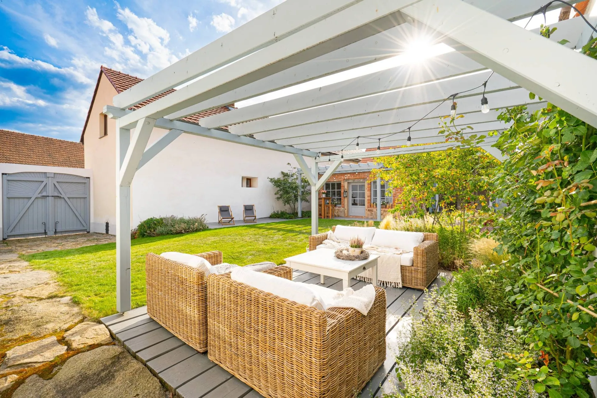 Rattan seating under the pergola looking across the lawn to the courtyard gates