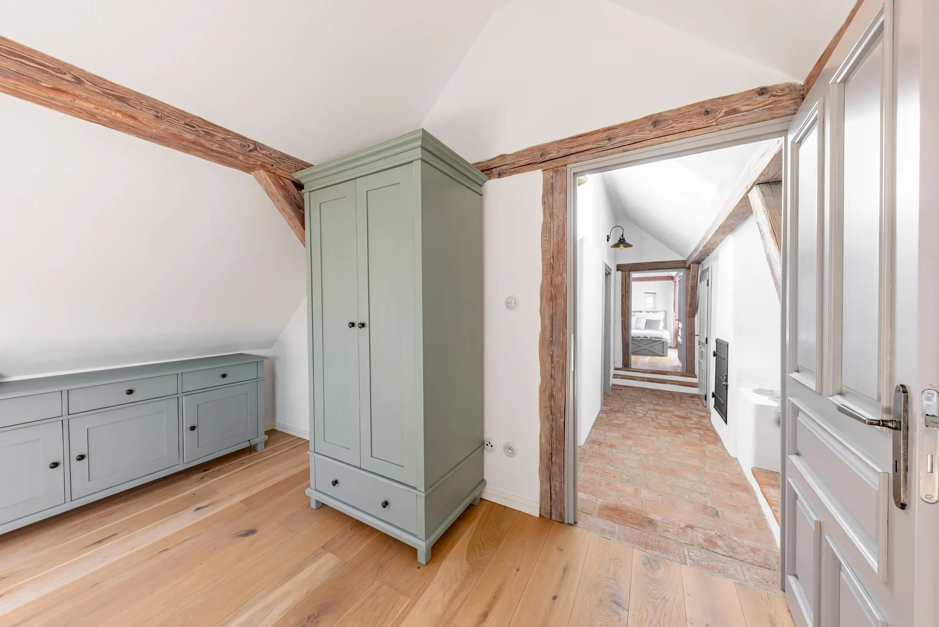 Attic room with a sage-green wardrobe, low sideboard and an open door onto the landing.