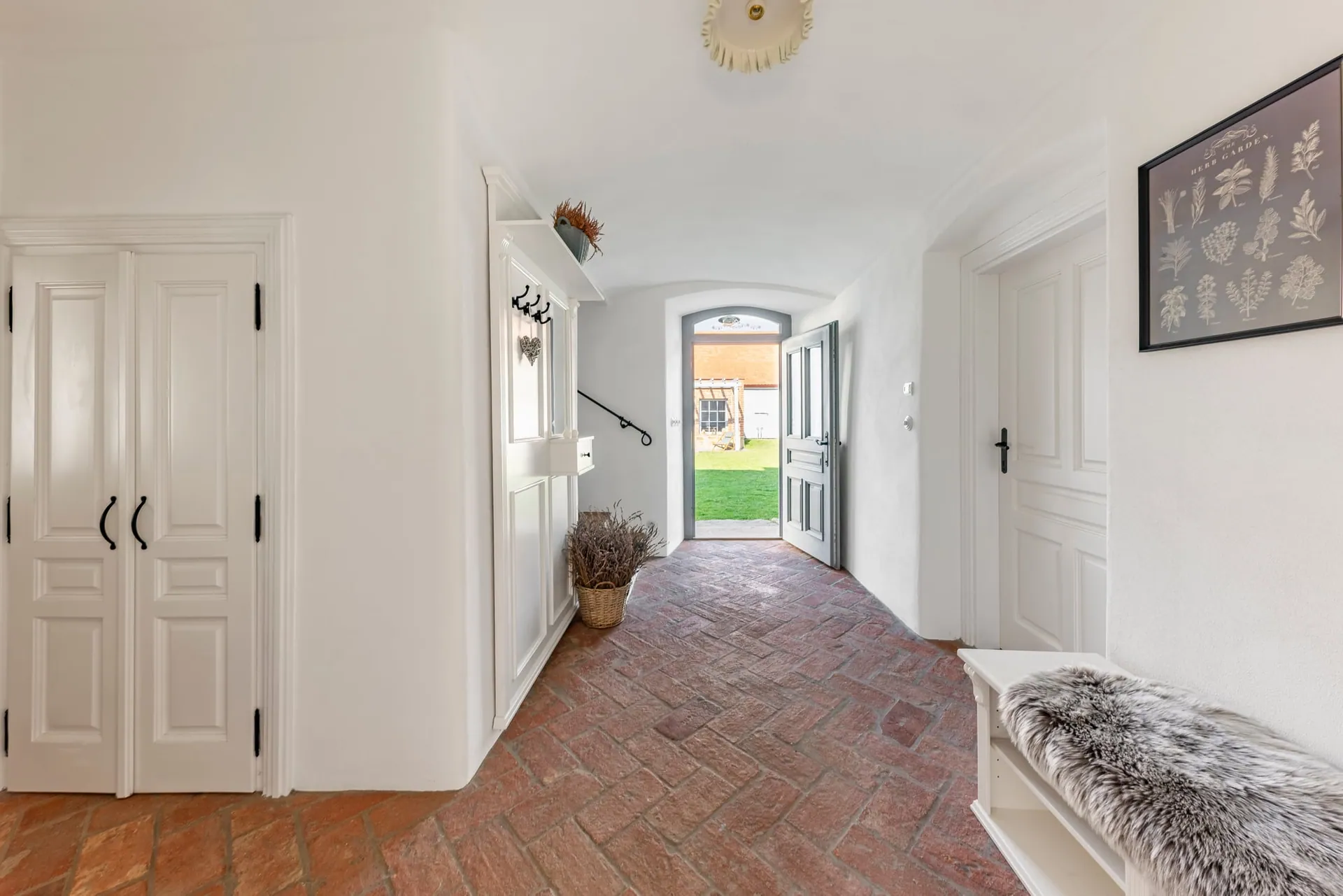 Vaulted entrance hall with a herringbone brick floor and a door open to the garden.