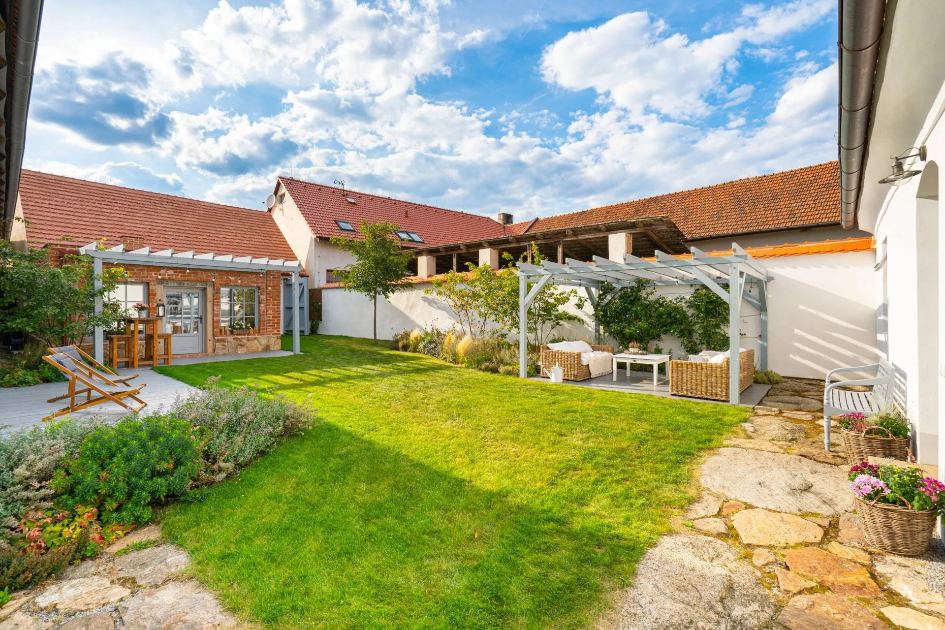 The sunny garden with its lawn, the garden house and seating under the pergola