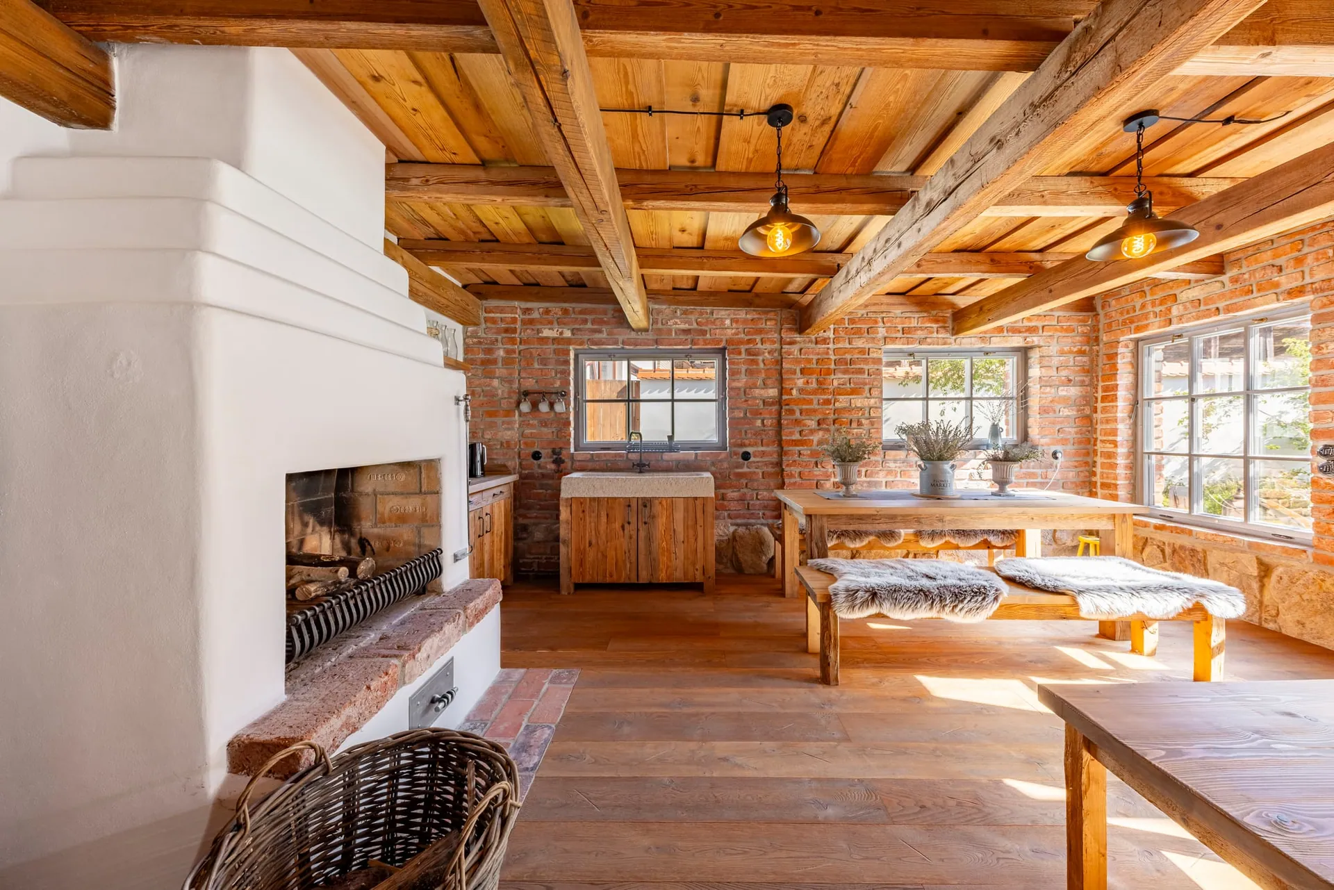 Garden house with a timber-beamed ceiling, open fireplace and long table with benches.