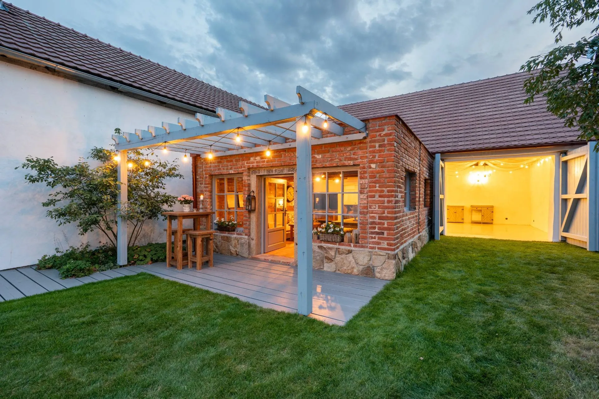 The garden house with its pergola and the open barn glowing with string lights