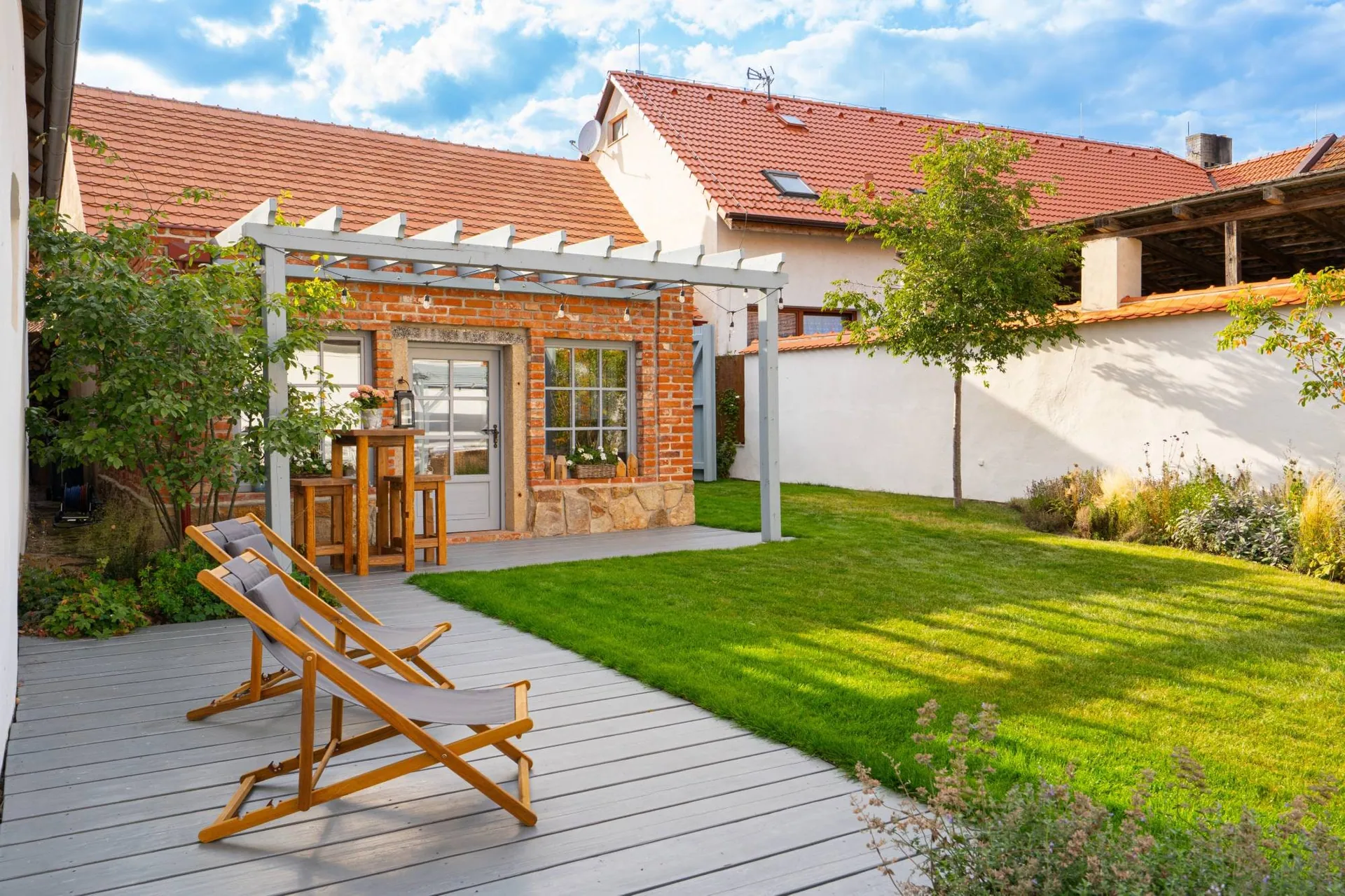 Deckchairs on the terrace in front of the garden house and its pergola