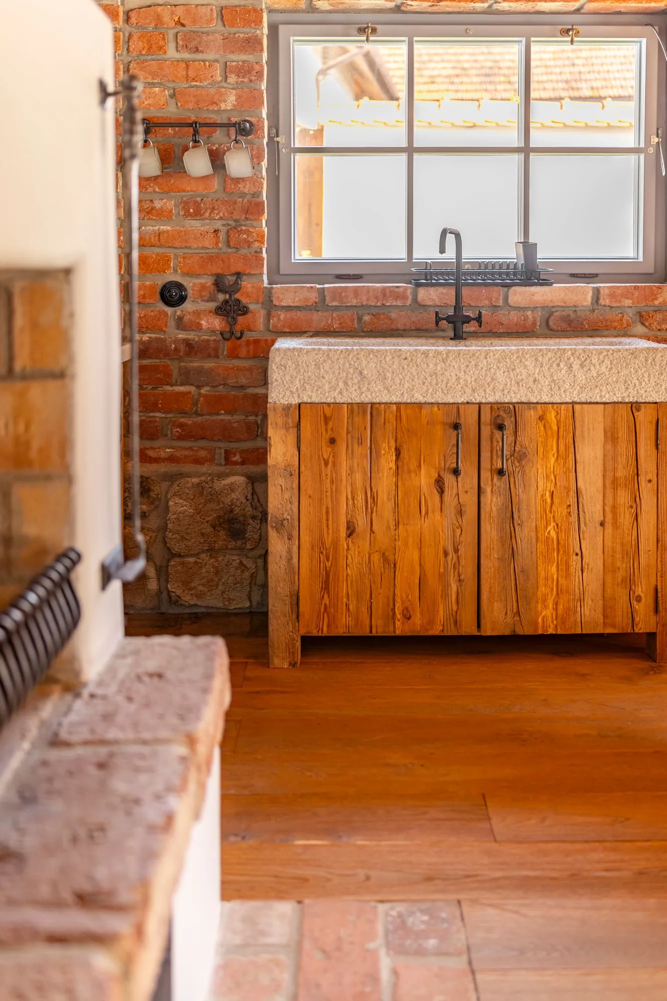 Stone sink on a weathered-wood cabinet beneath a window in the garden house.